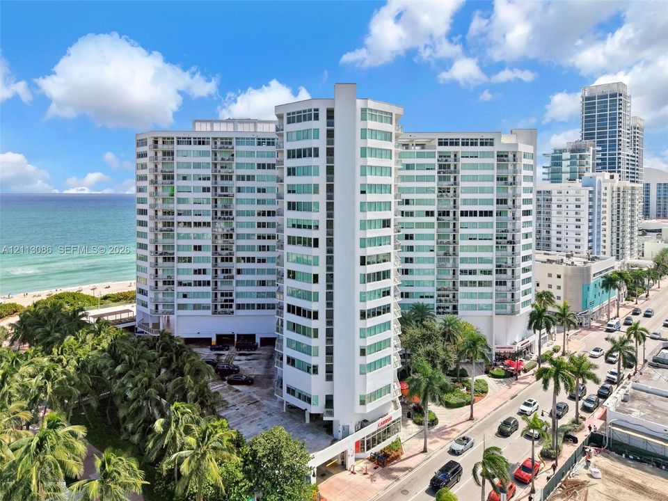High-rise residential building featuring a glass-paneled facade, private balconies, covered parking, and proximity to the oceanfront