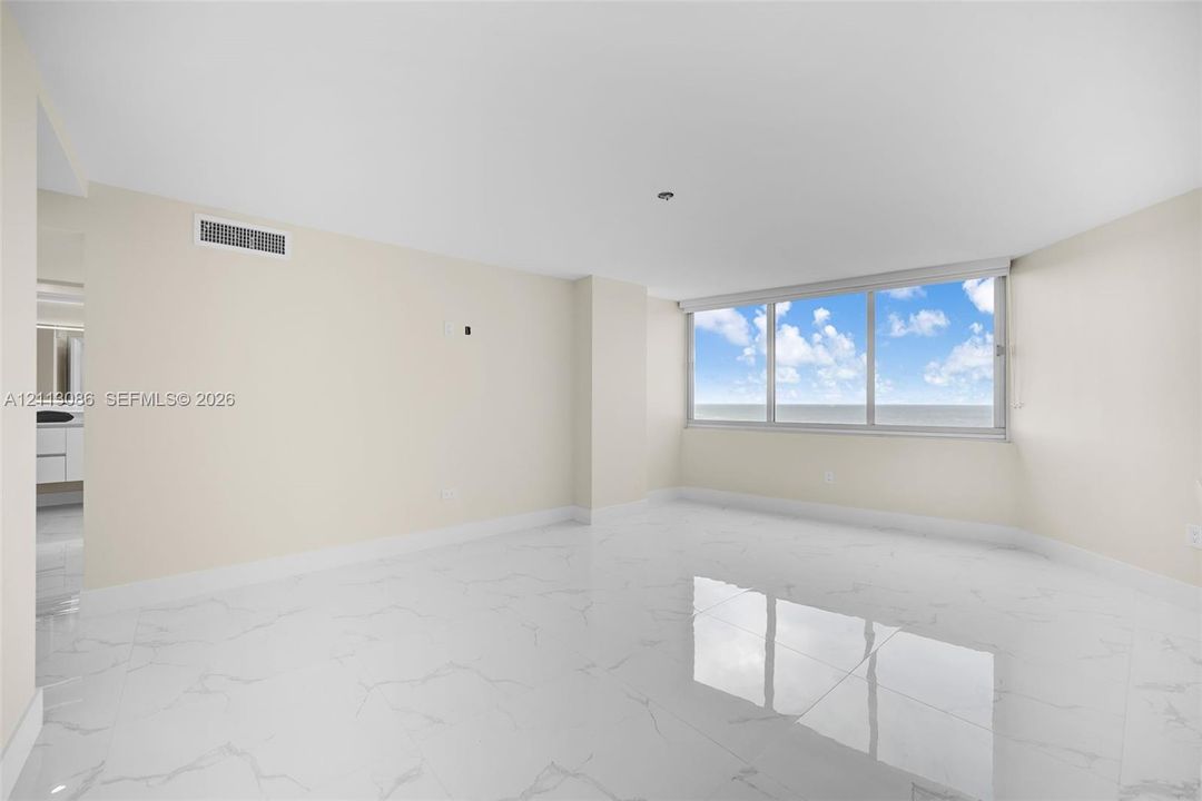 Bright interior space featuring polished stone-finish flooring, floor-to-ceiling windows, and neutral wall tones