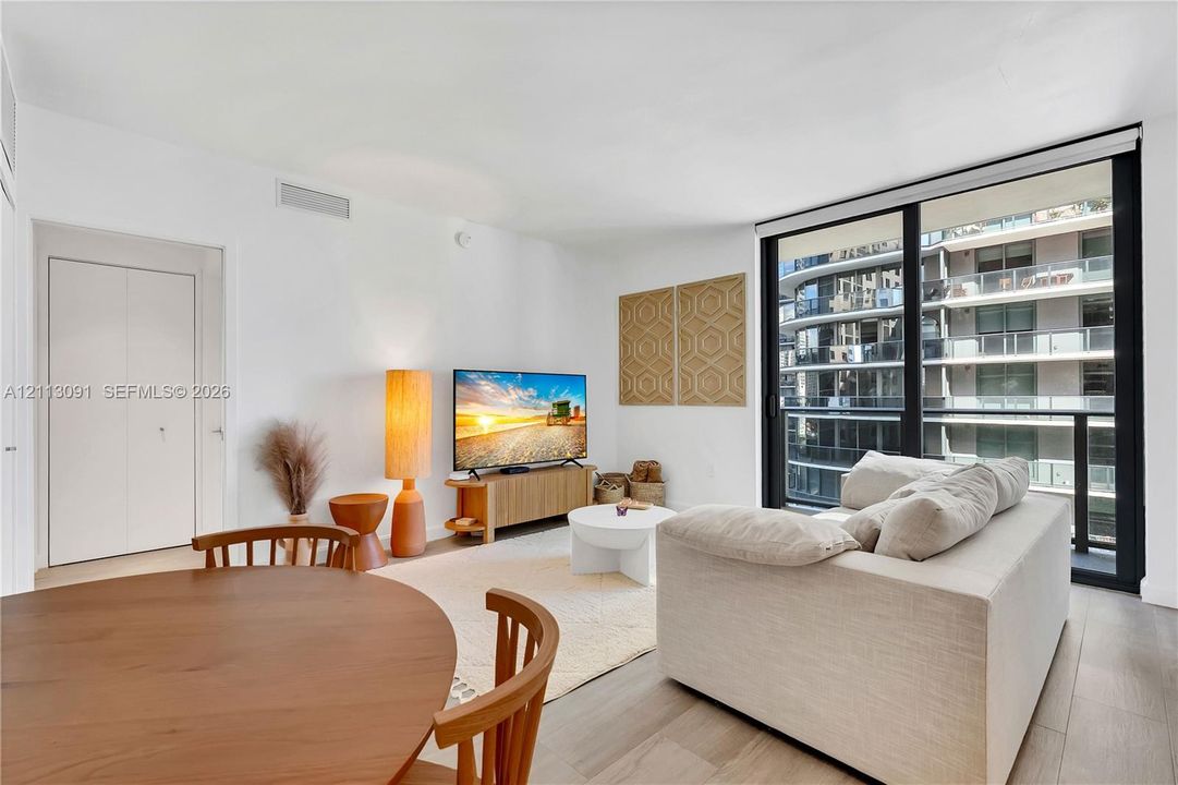 Open-concept interior featuring floor-to-ceiling glass panels, wood-finish flooring, and a private balcony
