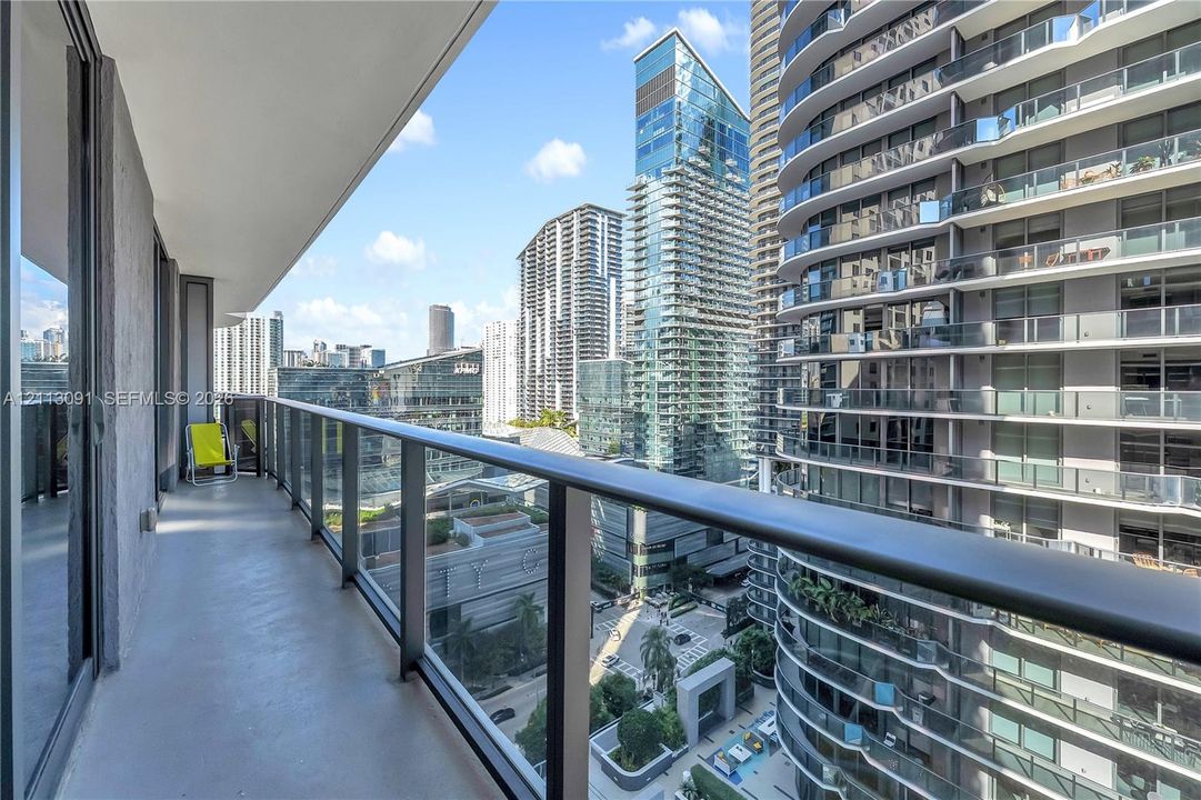 Covered balcony featuring concrete flooring and a glass panel railing with a matte black metal frame