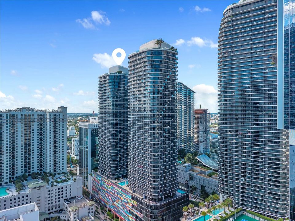 High-rise residential tower featuring a glass facade, private balconies, and a rooftop terrace