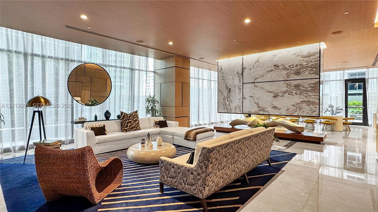 Open-concept interior featuring floor-to-ceiling windows, polished stone flooring, a ceiling finished in wood veneer, and a large-format decorative stone feature wall with integrated lighting