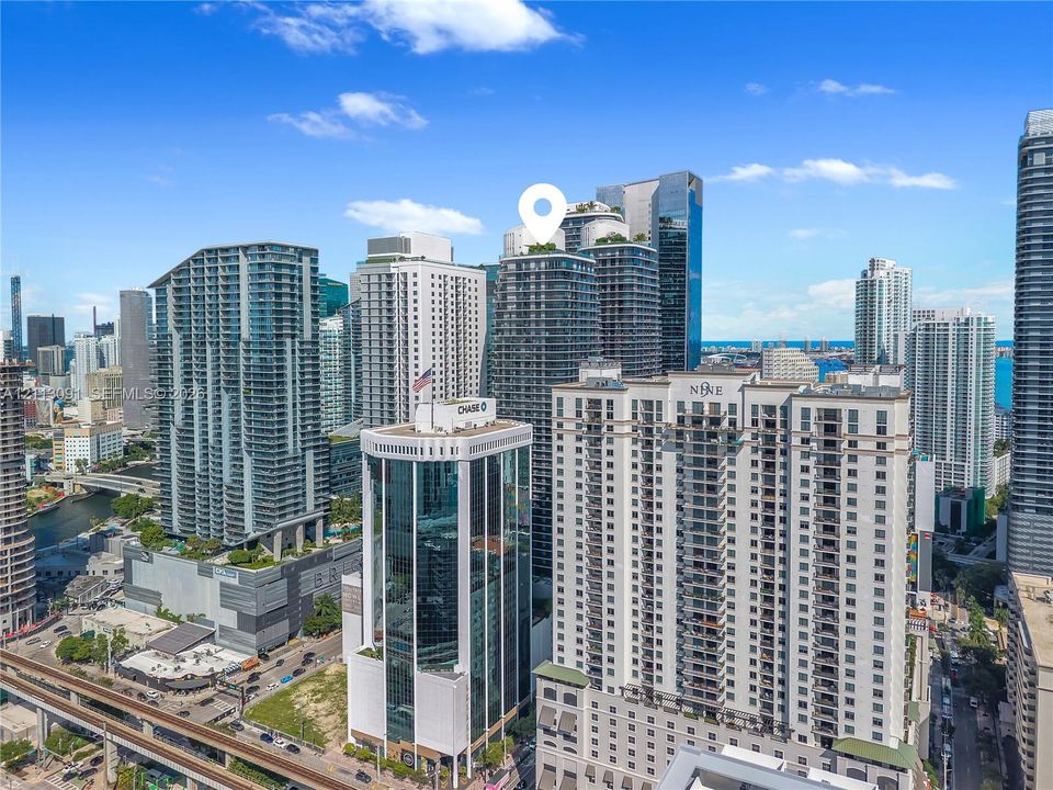 High-rise urban building featuring a glass curtain wall exterior, multi-level architectural design, and a rooftop terrace