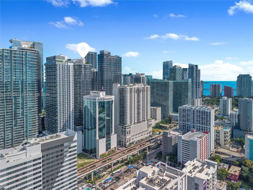 Aerial perspective of a high-rise tower featuring a glass facade, balconies, and a top-level outdoor terrace