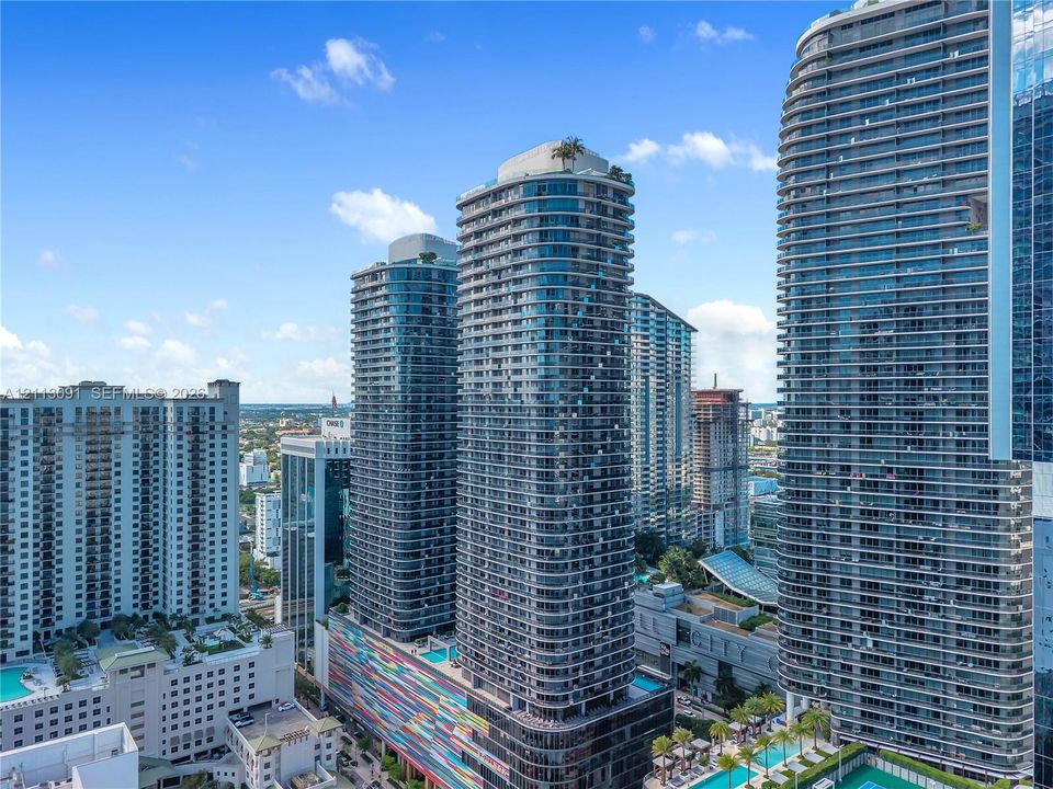 High-rise residential architecture featuring glass-curtain facades, tiered tower profiles, colorful mosaic podium detailing, and rooftop greenery