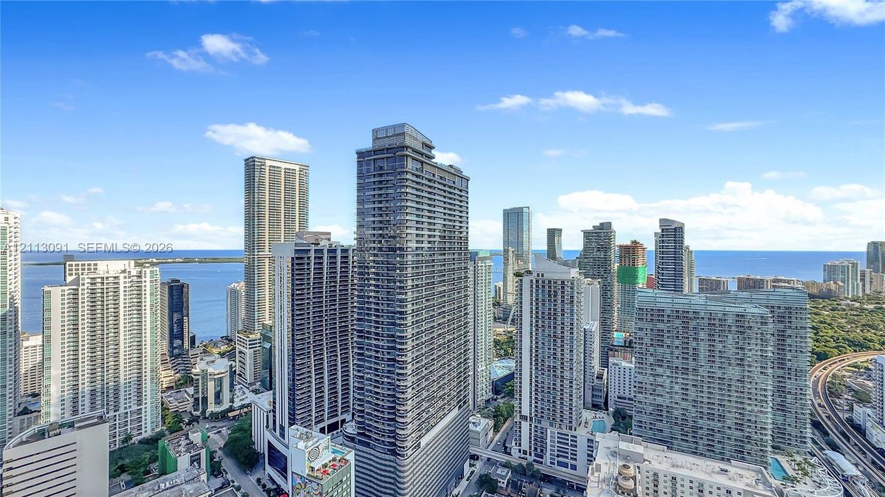 High-rise urban landscape featuring extensive glass facade architecture, proximity to the coastline, and expansive water horizons