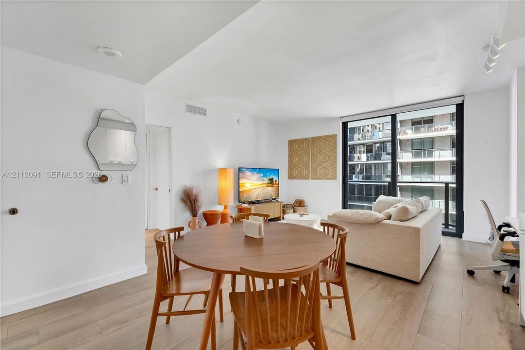 Open-concept living space featuring wood-finish flooring, floor-to-ceiling glass sliding doors, and recessed ceiling lighting