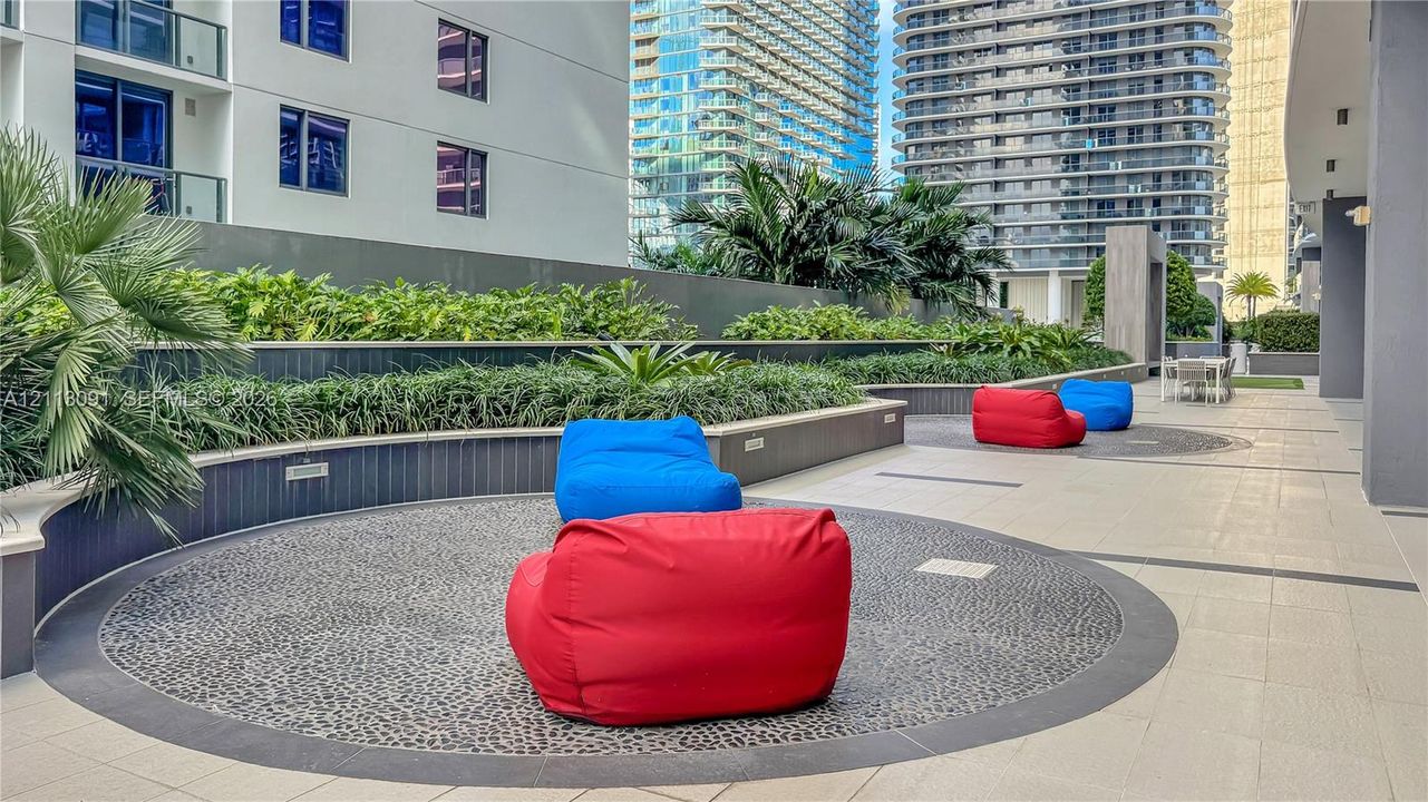 Outdoor terrace featuring patterned stone tiling, built-in curved retaining walls, integrated ground lighting, and manicured landscaping