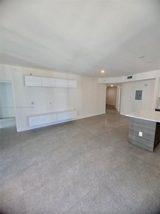 Large-format tile flooring throughout featuring floating white cabinetry, recessed lighting, and a kitchen island with a stone-finish countertop
