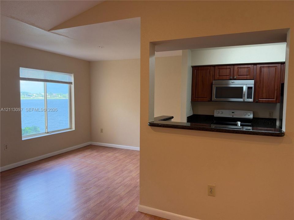 Open interior featuring wood-finish flooring, vaulted ceilings, and a passthrough kitchen window
