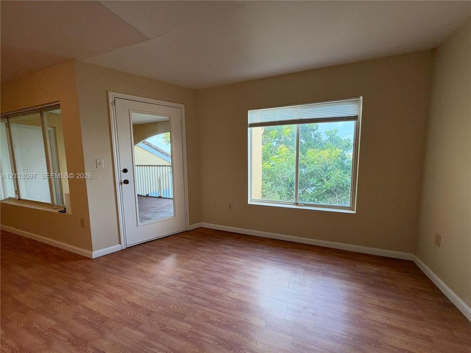 Interior space featuring wood-finish flooring, a glass-panel exterior door, and a multi-pane window with integrated blinds