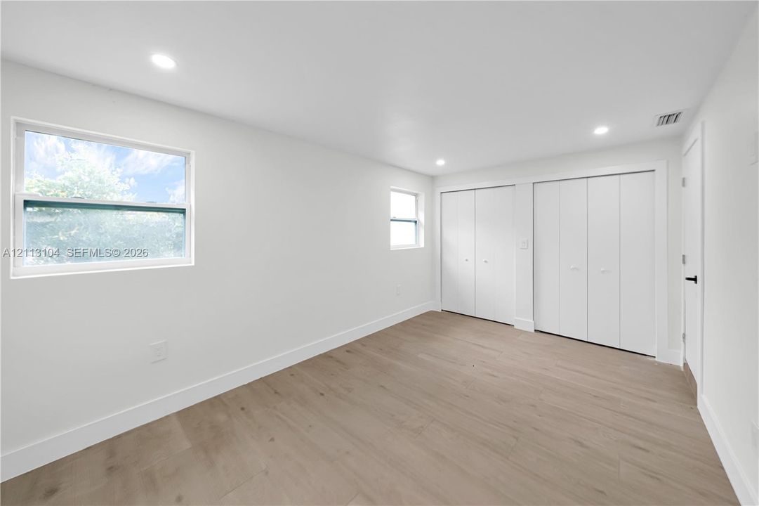 Interior space featuring wood-finish flooring, recessed lighting, and dual sets of bi-fold closet doors
