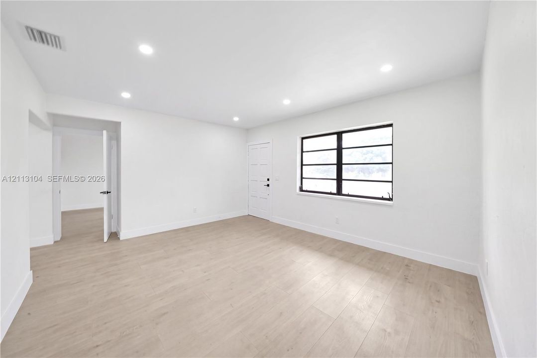 Bright room featuring wood-finish flooring, recessed lighting, and a window with dark-trimmed muntins