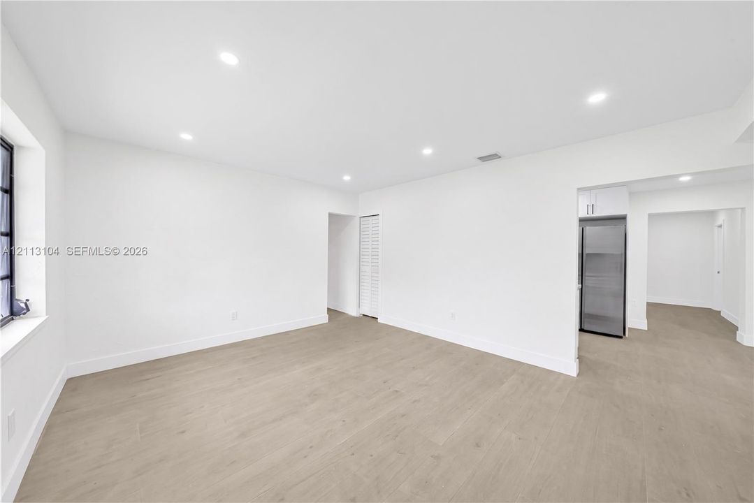 Neutral interior featuring light-tone wood-finish flooring, recessed lighting, and a stainless steel refrigerator