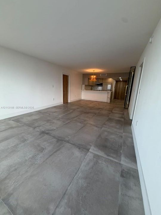 Large-format tile flooring, recessed ceiling lighting, and a kitchen featuring an extended peninsula with a stone-finish countertop