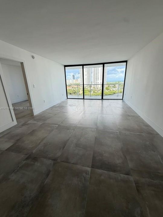 Floor-to-ceiling glass windows, large-format tile flooring, and integrated balcony access