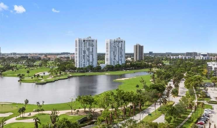 Aerial perspective featuring a large lake, sprawling golf course fairways, mature landscaping, and multi-story high-rise buildings