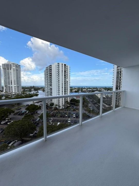 Covered balcony featuring concrete flooring and a white metal railing
