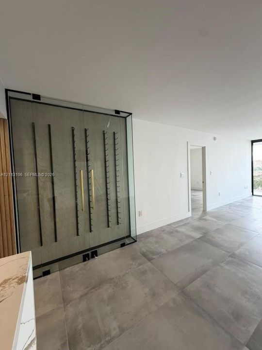 Custom glass-enclosed display storage featuring dark metal racking, metallic hardware, large-format tile flooring, and clean minimalist wall finishes