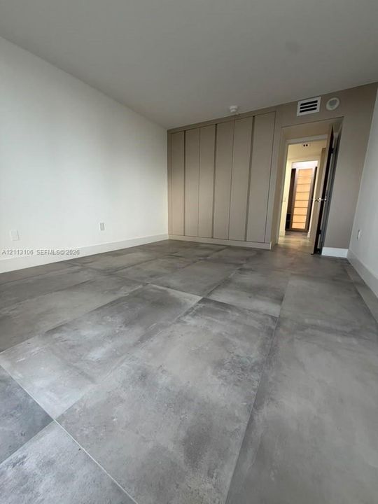 Large-format gray stone tile flooring, floor-to-ceiling built-in cabinetry with flush-panel doors, and neutral wall finishes
