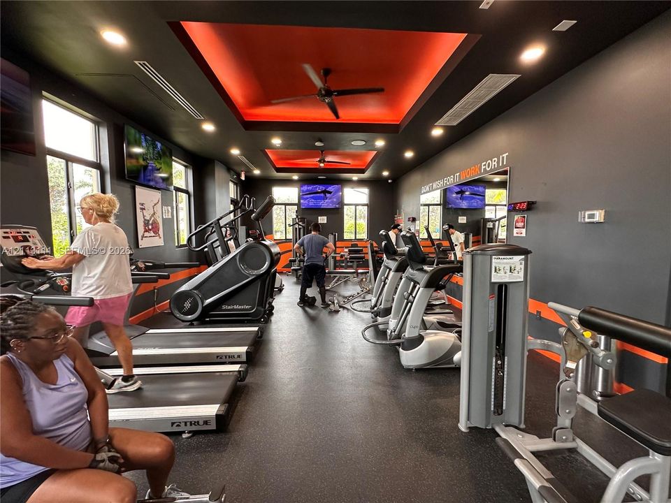 Fitness room featuring recessed tray ceilings with integrated lighting, oversized windows, and rubberized flooring