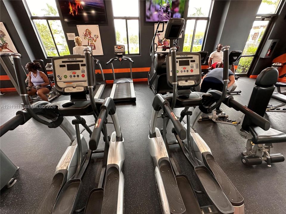 Fitness center featuring rubber flooring, floor-to-ceiling windows, and multiple elliptical and treadmill machines