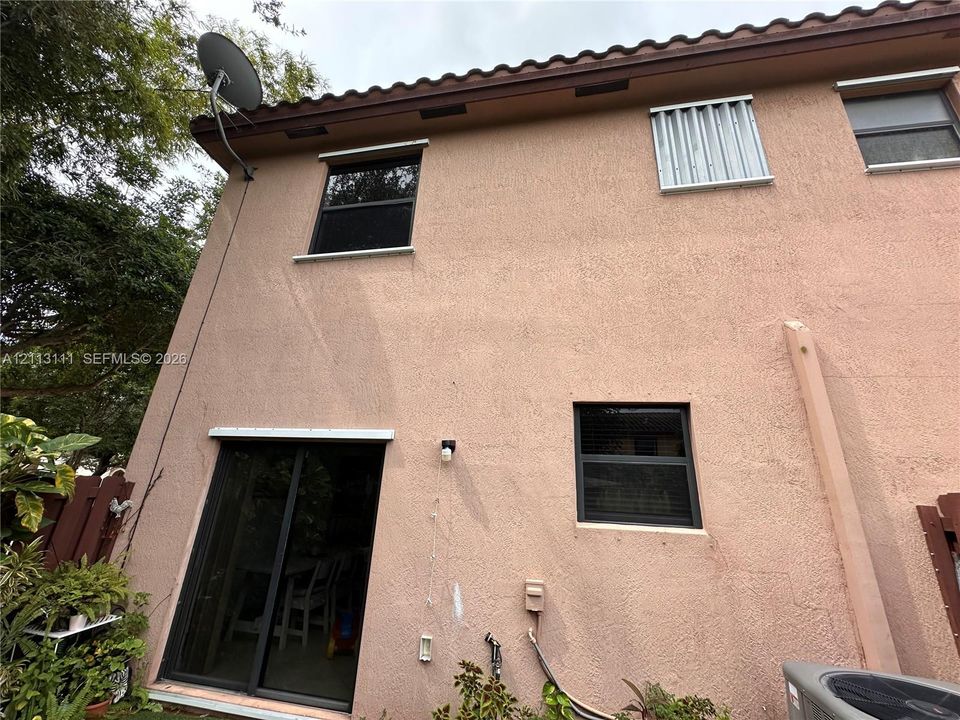 Stucco exterior featuring dark-framed windows, sliding glass door, and a traditional tile roofline