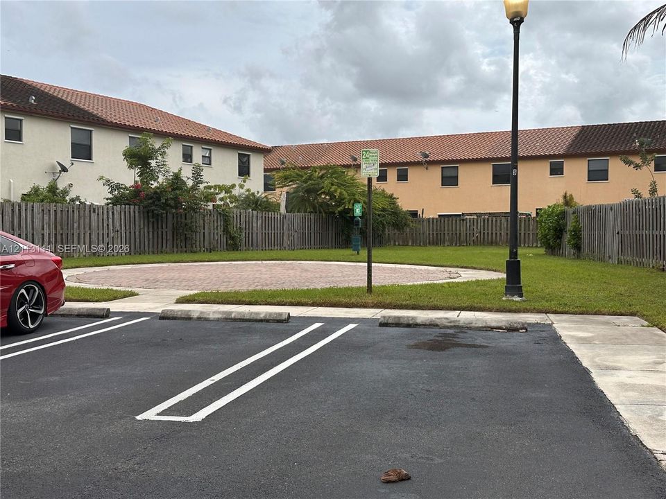 Common area featuring paved parking, a circular brick hardscape, and perimeter wood fencing