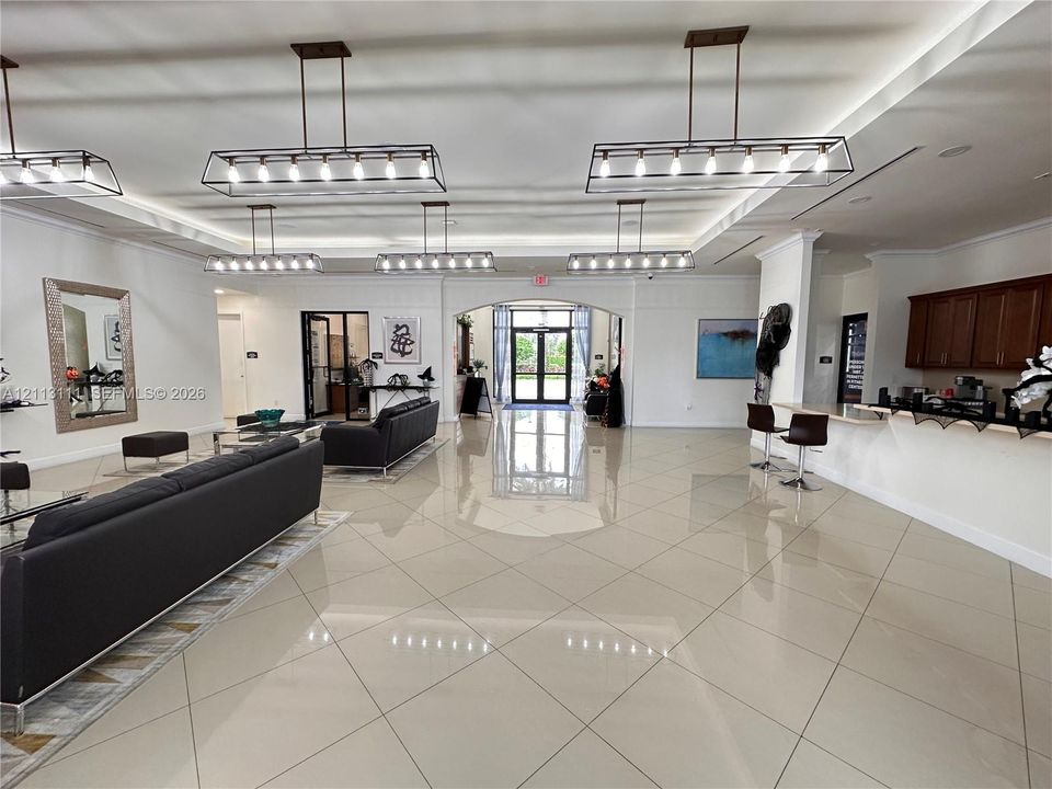 Large interior space featuring high ceilings with recessed lighting, oversized tile flooring, multiple linear pendant light fixtures, and built-in cabinetry
