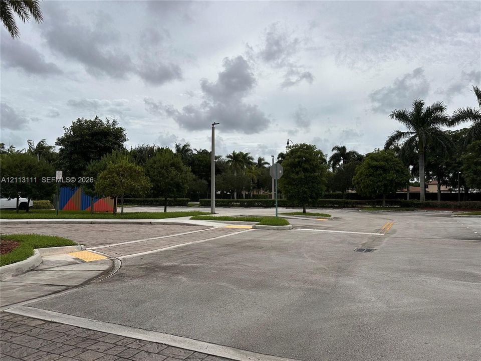 Paved parking area featuring concrete curbing, landscaped medians, mature trees, and designated pedestrian pathways