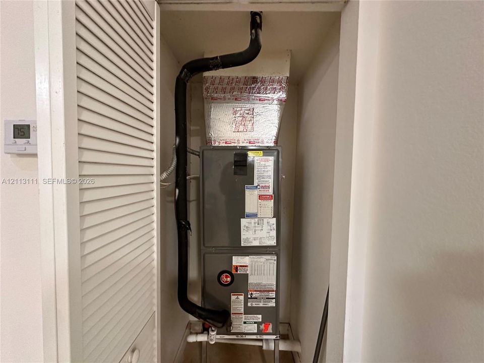 HVAC system featuring a furnace unit, insulated ductwork, and a digital wall-mounted thermostat