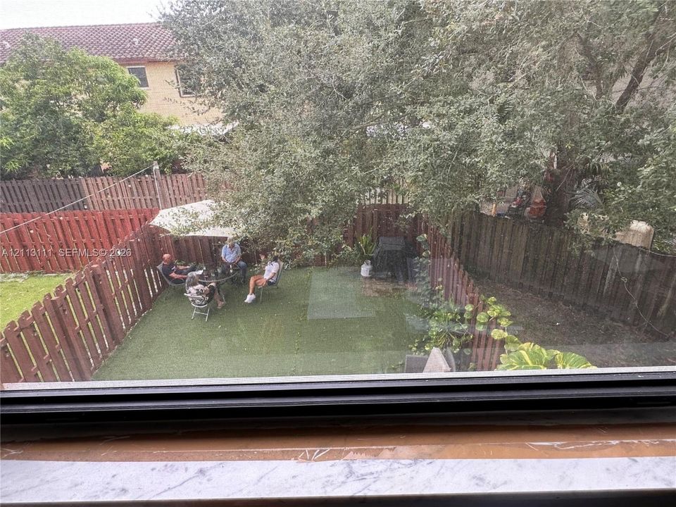 Backyard featuring synthetic turf, wood privacy fencing, and mature trees