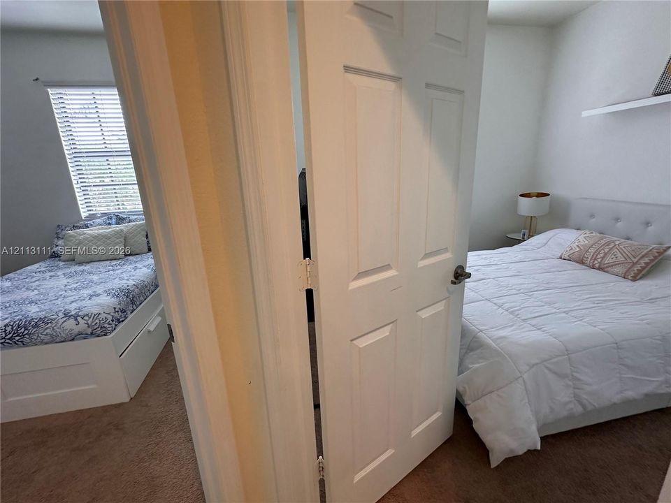 Six-panel interior door, carpeted flooring, and wall-mounted shelving