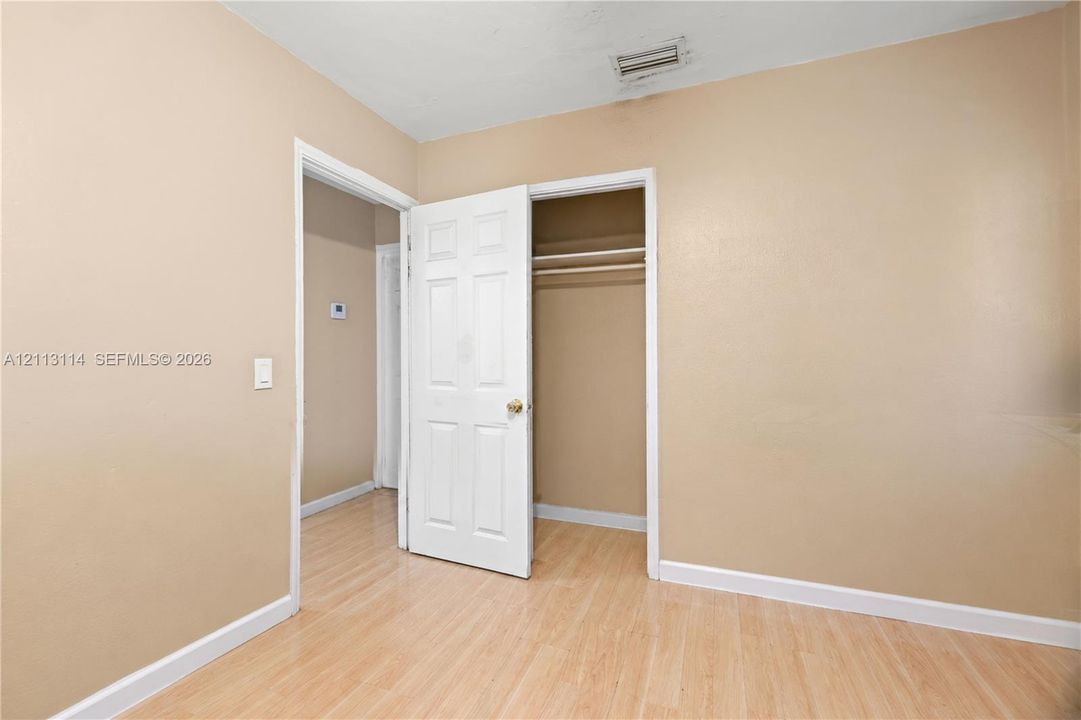 Neutral wall paint, light wood-finish flooring, and a closet featuring a white six-panel door and interior shelving