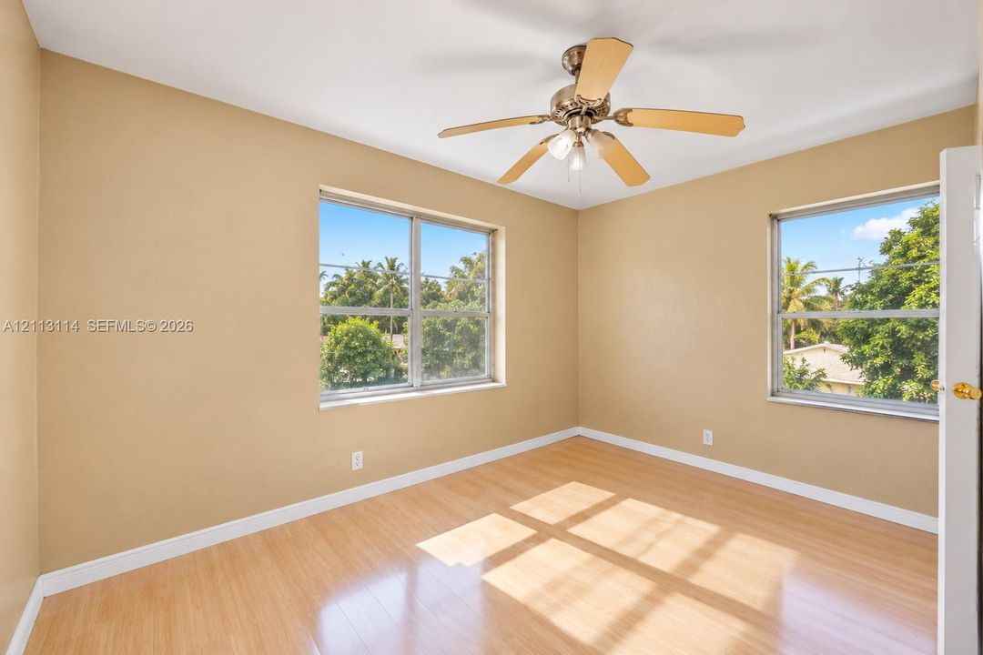 Wood-finish flooring, dual windows, and a ceiling fan with integrated lighting