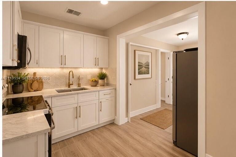 AI-generated photo of the kitchen featuring white shaker-style cabinetry, stone-patterned countertops, a patterned tile backsplash, under-cabinet lighting, and wood-finish flooring