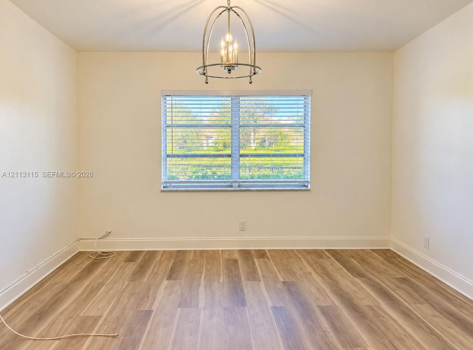 Wood-finish flooring, central metal cage chandelier, and window with horizontal blinds