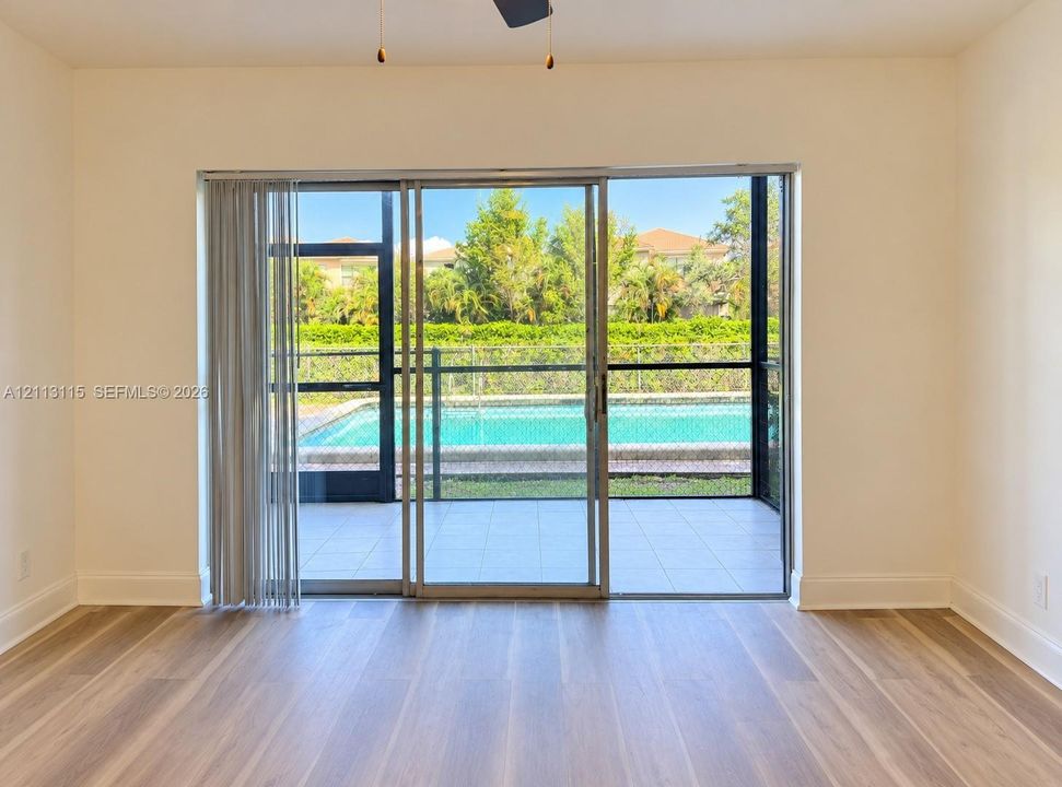 Wood-finish flooring, large sliding glass doors, and a screened-in patio featuring an in-ground swimming pool