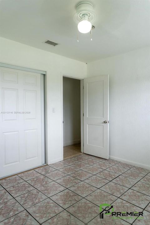 Tiled flooring, dual-panel sliding closet doors, and interior paneled door featuring metallic hardware