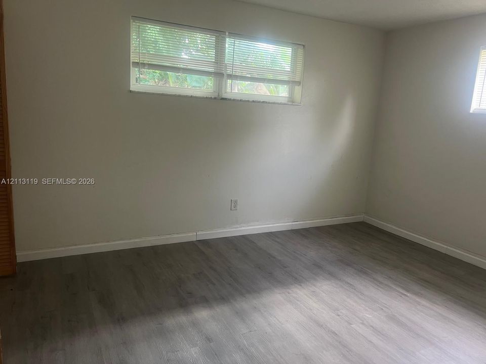 Room featuring neutral wall paint, wood-finish flooring, and horizontal window blinds