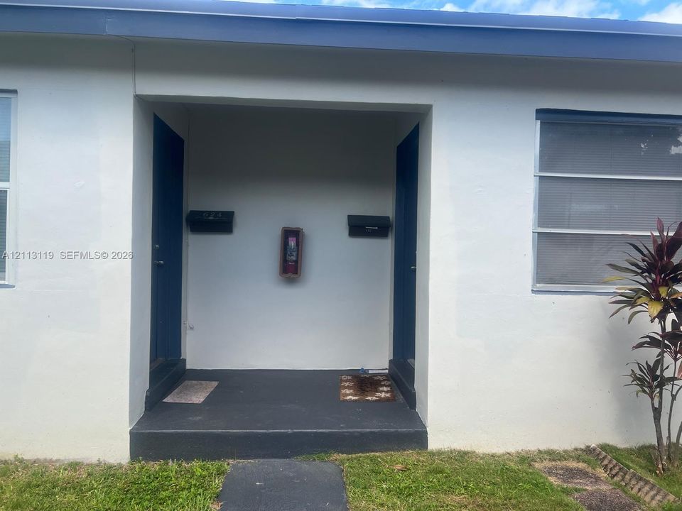 Exterior facade featuring stucco siding, two solid entry doors, dual mounted mailboxes, and a recessed covered concrete stoop