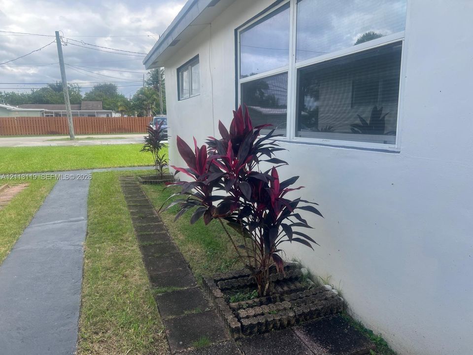 Exterior featuring white siding, dual-pane windows, and landscaped garden beds with concrete edging