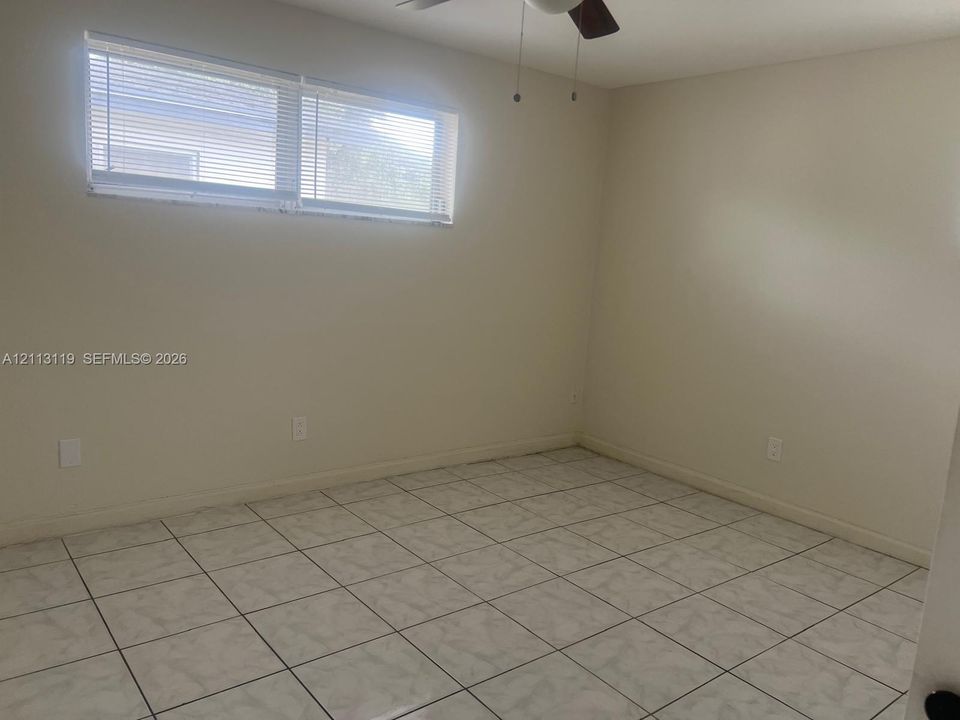 Room featuring neutral-toned walls, tiled flooring, horizontal window blinds, and a ceiling fan