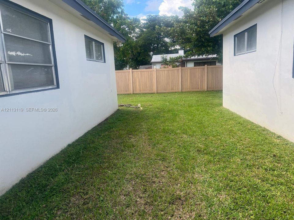 Exterior side yard featuring stucco walls, horizontal slider windows, and a solid-panel privacy fence