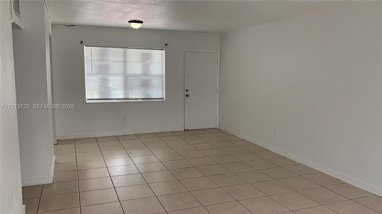 Interior space featuring ceramic tile flooring, neutral wall finishes, a window with horizontal blinds, and a flush-mount ceiling light fixture