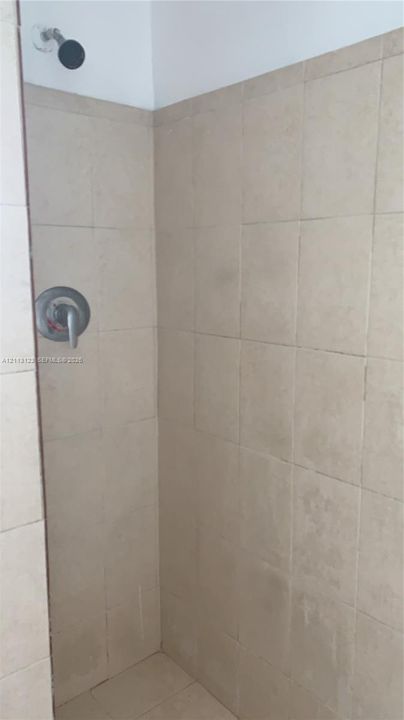 Shower enclosure featuring neutral-toned tile wall cladding, a single-handle pressure-balanced faucet, and a wall-mounted shower head
