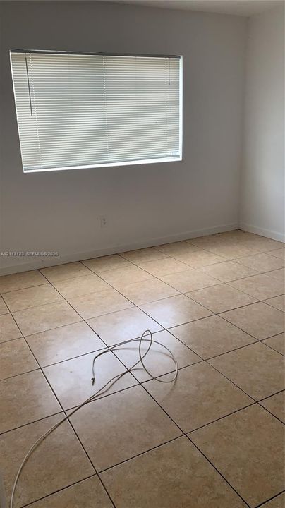Neutral-toned ceramic tile flooring and a horizontal window featuring integrated blinds