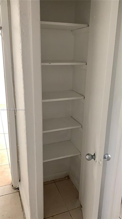 Built-in storage closet featuring five painted shelves and a standard swing door