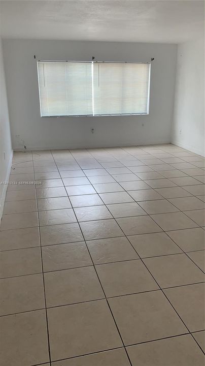 Neutral interior space featuring large-format ceramic tile flooring and a wide dual-pane window