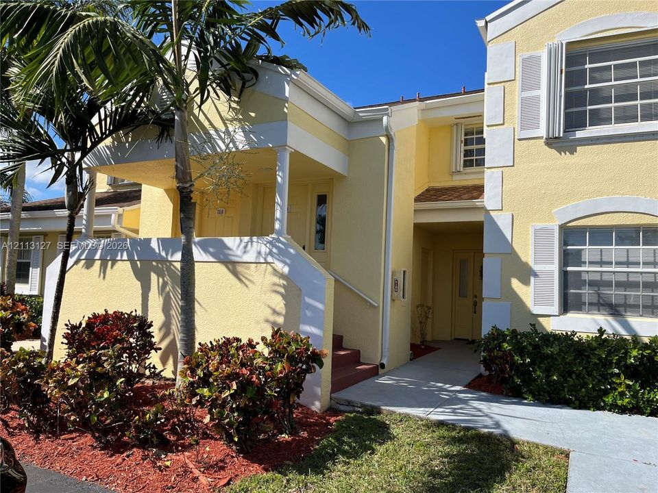 Stucco exterior featuring dual-tone trim, covered entry porch with decorative columns, and multi-pane windows with operable shutters